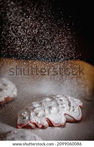 Sprinkle icing sugar over the Christmas cookies.