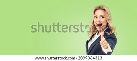 Happy smiling businesswoman in grey suit, showing thumbs up gesture, over light green color background. Business success concept. Copy space for text. Executive, employee, female manager, professional