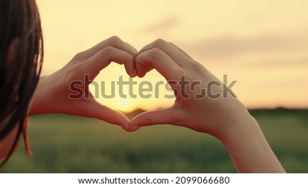 Healthy heart concept. The girl molded a love heart from her palms. Happy girl making heart shape with fingers. The light of the summer spring sun is in my hands. Travel, relax in nature.