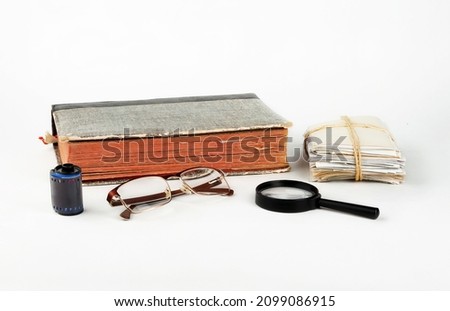 Albums with old family photos, glasses and a magnifying glass on a white background.