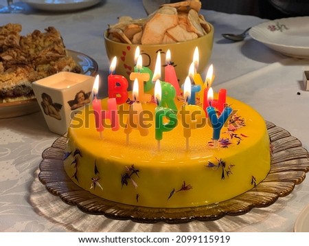 little yellow birthday cake with lit candles 