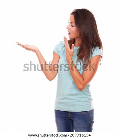 Portrait of surprised lady holding her right hand up and looking to her while standing on isolated white background - copyspace