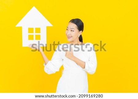 Portrait beautiful young asian woman with house or home paper sign on color background