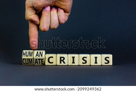 Climate or human crisis symbol. Businessman turns wooden cubes and changes words climate crisis to human crisis. Beautiful grey background, copy space. Ecological climate or human crisis concept.
