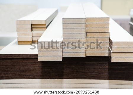 Chipboard furniture parts are on the workbench of the production workshop. Close-up Royalty-Free Stock Photo #2099251438