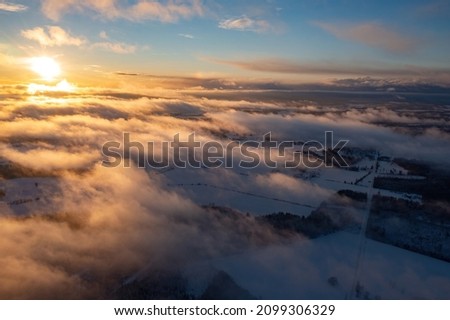 Aerial view of sunset above snow covered trees in a winter forest Royalty-Free Stock Photo #2099306329