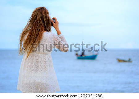 Woman holding vintage camera taking photo on beach