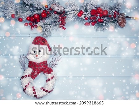 christmas snowman toy winter branches cones and snow on blue wooden texture                              