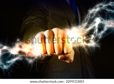 Close up of businessman hand holding lightning in fist Royalty-Free Stock Photo #209931883