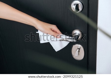 Cleaning black door handles with an antiseptic wet wipe. Woman hand using towel for cleaning home room door link. Sanitize surfaces prevention in hospital and public spaces against corona virus.