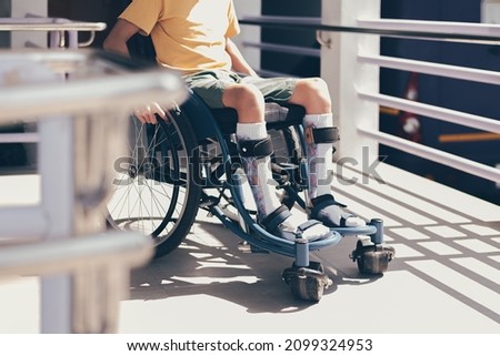 Young man with disability using wheelchair by himself on public ramps in hospitals or schools background, Pictures of the facilities or equipment and transportation for people with disabilities.