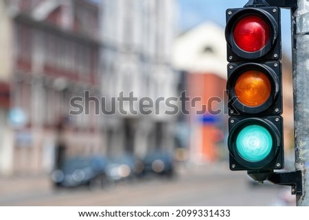 close-up of small traffic semaphore with green light against the backdrop of the city traffic Royalty-Free Stock Photo #2099331433