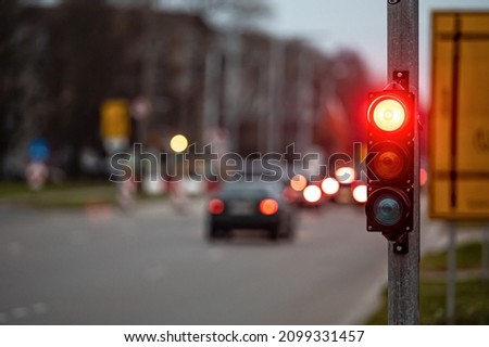 a city crossing with a semaphore on blurred background with cars in the evening streets, red light Royalty-Free Stock Photo #2099331457