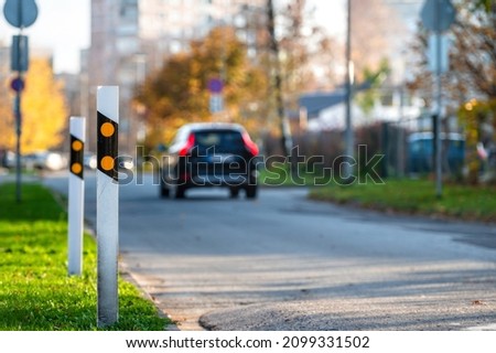poles at the traffic safety speed bumps in residential area, blurred background with a car, closeup