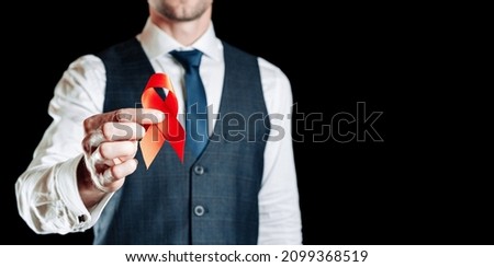 Hiv day. Red ribbon in hiv world day isolated on black background. Man holding awareness aids and cancer symbol. Aging Health month concept