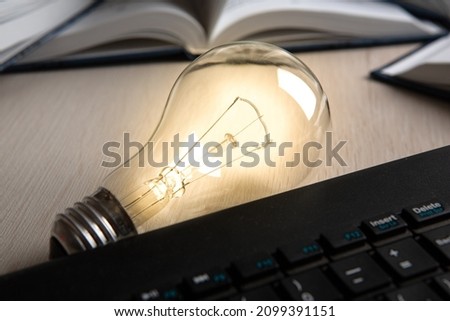 burning glass bulb on the background of books and pc keyboard