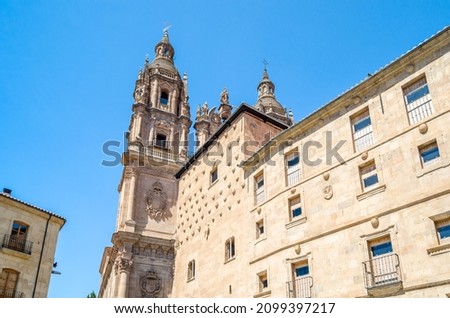Architecture in Salamanca, Spain. Facade of Casa de las Conchas a building mixing late Gothic and Plateresque style, decorated with more than 300 shells and a Baroque church in the background