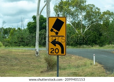 Warning road sign of sharp bend in country road Royalty-Free Stock Photo #2099401153