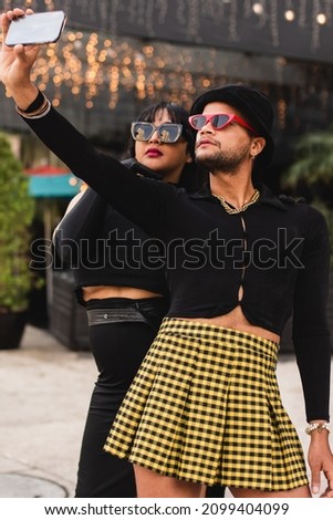 Two non binary guys posing for a selfie on the street