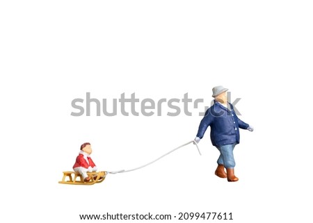 Miniature people Father towing sledge with child isolated on white background with clipping path
