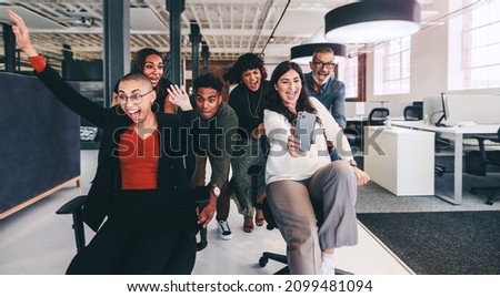 Capturing fun moments. Cheerful businesswoman taking a selfie with her colleagues during playtime. Group of businesspeople having fun and celebrating their success in a modern workplace.