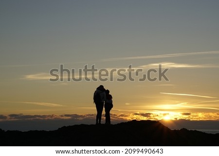 A mother and a son in front of the sunset of the sea, on an artificial sand dune, for the nourishment of the beach after the storms.