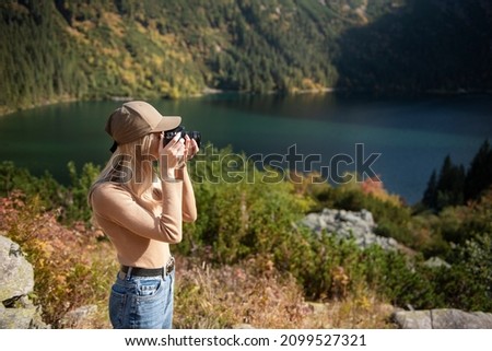 Photographer tourist traveler standing on green top on mountain holding in hands digital photo camera. Hiker taking  photography, girl enjoy nature panoramic landscape in trip