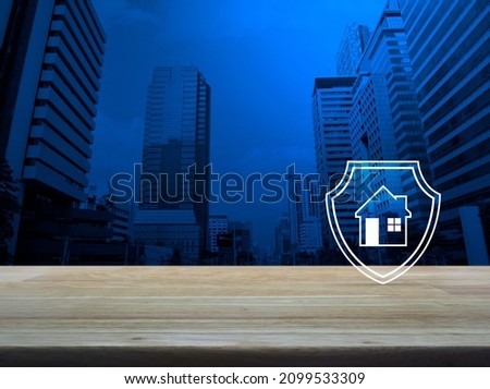 House with shield flat icon on wooden table over modern office city tower and skyscraper, Business home insurance and security concept