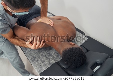 Qualified Caucasian osteopathic physician treating shoulder subluxation Royalty-Free Stock Photo #2099535013