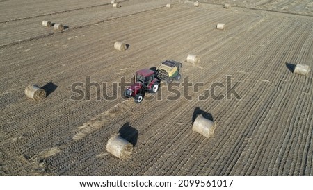 Farmers use agricultural machinery to compress rice straw and bundle them on a farm in North China