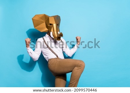 Photo of wacky lucky guy dressed wild animal mask rising fists empty space isolated blue color background