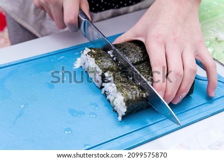 The girl neatly cuts the sushi made at home.
