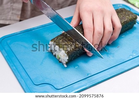 The girl neatly cuts the sushi made at home.