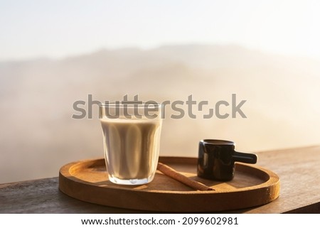 Sunrise coffee in nature. Milk with coffee shot on wooden table with mountain fog on shade of sunrise background. Good morning.