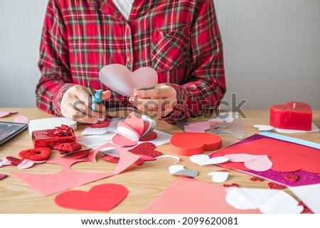 DIY holiday card with red paper heart, symbol of love. Girl  makes Mother's Day, Valentine's Day, greeting card. Hobby,  art concept, gift with your own hands