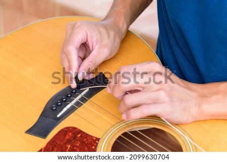 The musician replace the new guitar strings for his guitar Royalty-Free Stock Photo #2099630704