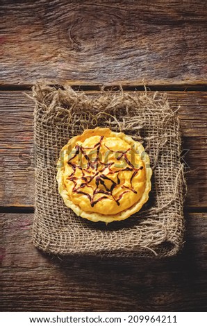 tartlet with pumpkin cream for Halloween for kids on a dark wood background. toning. selective focus to the middle of the tartlet