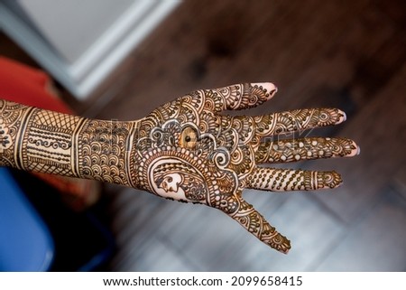 Drawing Henna art on the hand of Indian bride