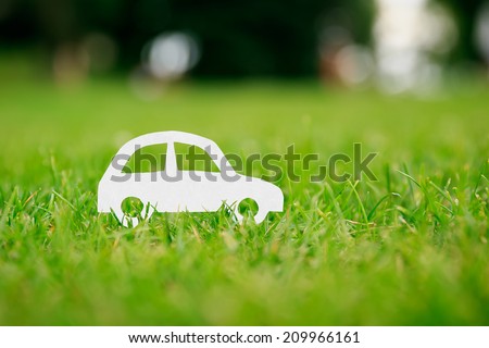 Paper cut of car on green grass
