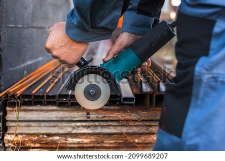 A man outdoors cuts a rebar with a grinder, close-up, beautiful sparks