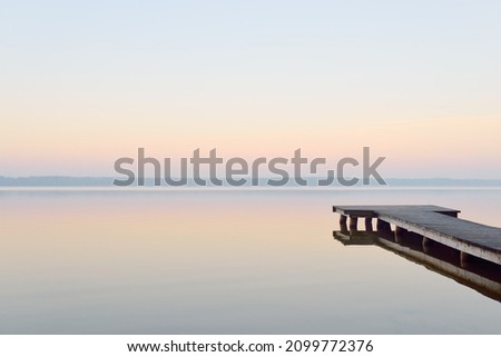 Forest lake (river) at sunrise. Wooden pier (boardwalk). Soft sunlight, mist, reflections on water. Idyllic autumn landscape. Pure nature, ecotourism, hiking, exploring Royalty-Free Stock Photo #2099772376