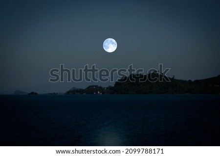 Bright white full moon over the mountains in the sea