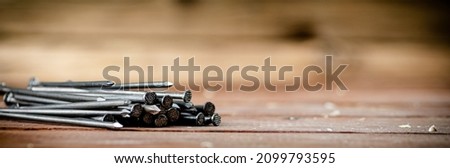 A pile of nails on the table. On a wooden background. High quality photo