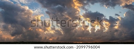 Leaden, storm clouds covered the sunset. Cumuliform cloudscape on blue sky. Tragic gloomy sky. Royalty-Free Stock Photo #2099796004
