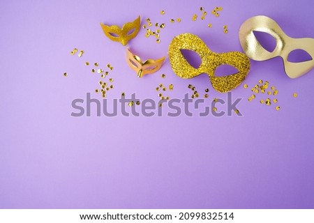 Carnival or mardi gras background with golden carnival masks on violet background. Top view with copy space