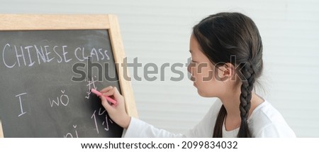 Banner Picture of Asian Girl Writing Chinese Language on Blackboard in Classroom
