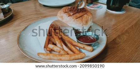 Kuala Lumpur, Malaysia 1 Dec. 2021: Fish burger with fries set and chili sauce lunch at cafeteria. Selective focus.