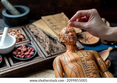 The doctor is pricking acupuncture with a model.Chinese character translation：Drawing acupuncture Royalty-Free Stock Photo #2099855005