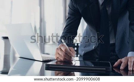 Businessman, manager using stylus pen signing e-document on digital tablet with laptop computer on table at modern office, e-signing, electronic signature, paperless office, digital document concept