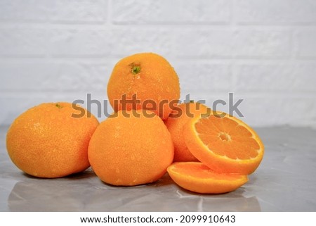 Tangerines on a light background. One tangerine is cut. 5 tangerines.